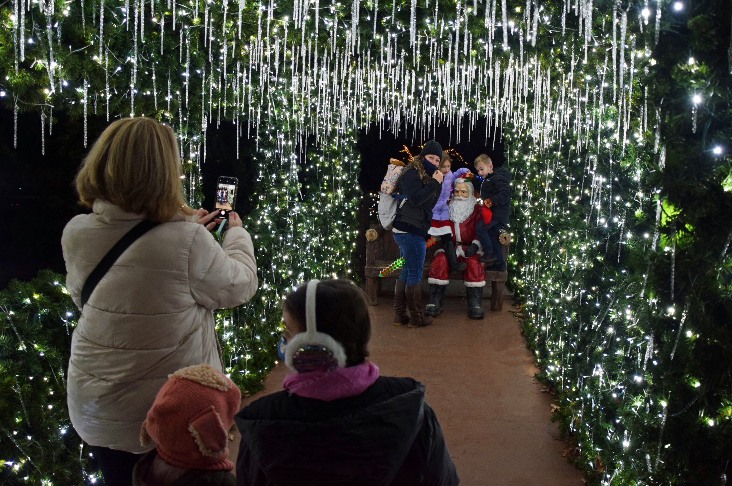 Crystal Bridge - covered footbridge adorned with garland and holiday lights, with a statue of Santa Claus sitting on a bench at the end of the bridge