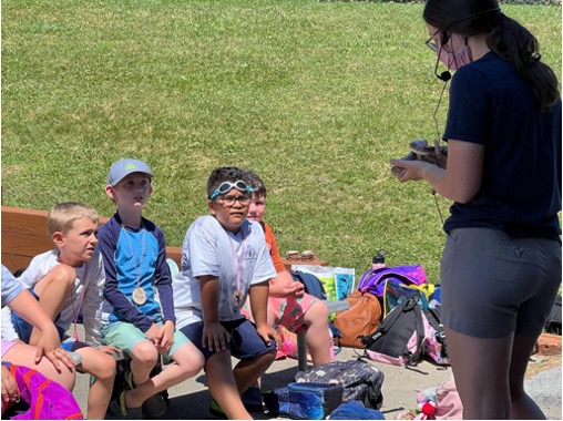 A conservation education intern holding a snake and giving a presentation to a crowd of children