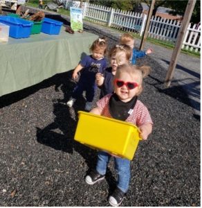 Photo of children at Preston's Place. Child in front is holding a small yellow tub