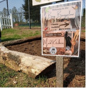 Photo of a sign at Preston's Place featuring the "Bug Bungalow" and the "Mud Kitchen"