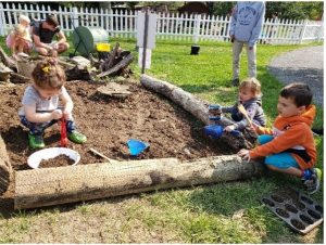 Photo of children participating in a nature play activity that involves digging in the dirt