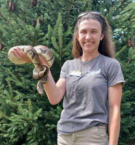 Photo of conservation educator Cassidy holding a large snake